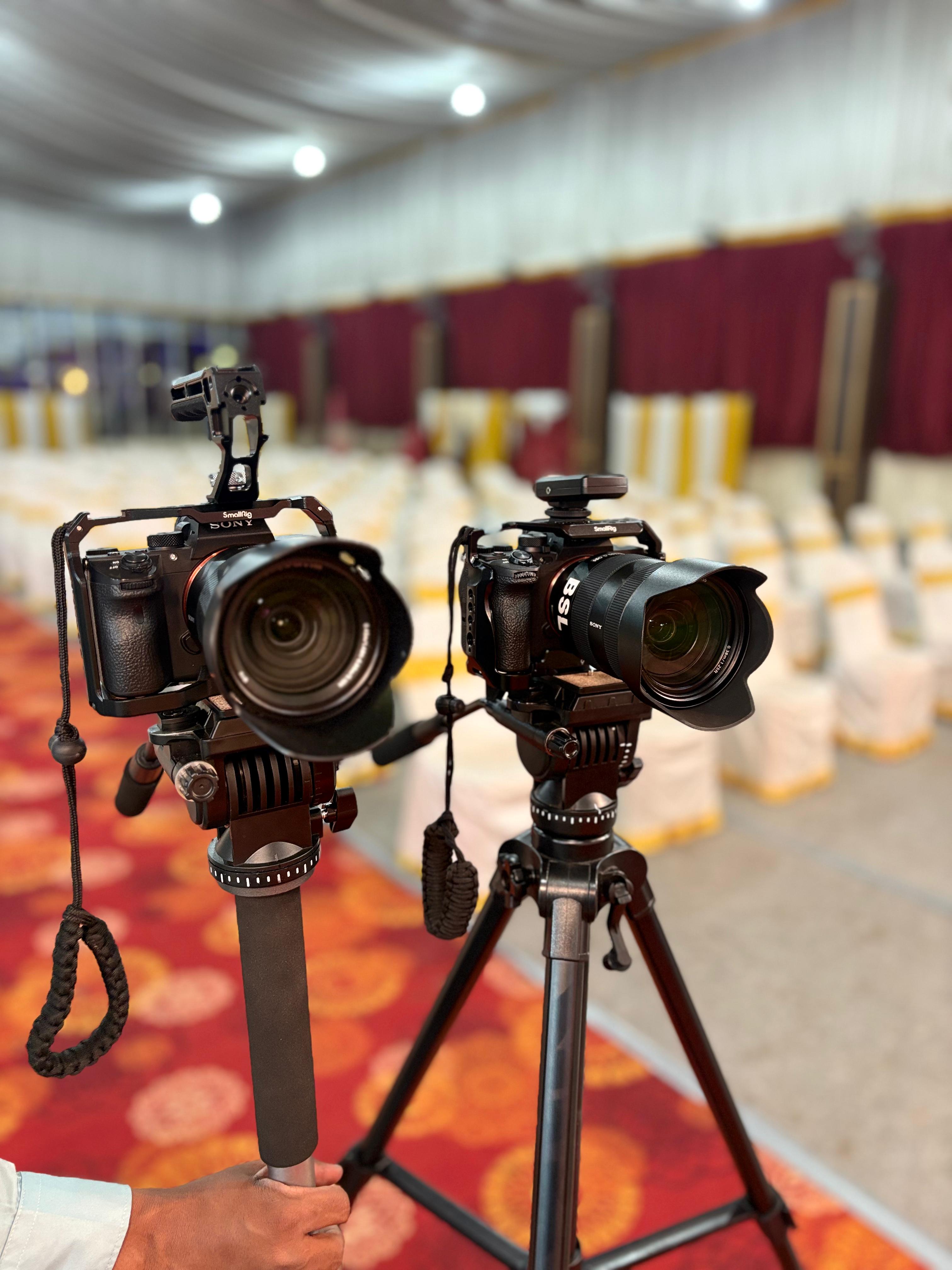 Two cameras on tripods set up to cover an event