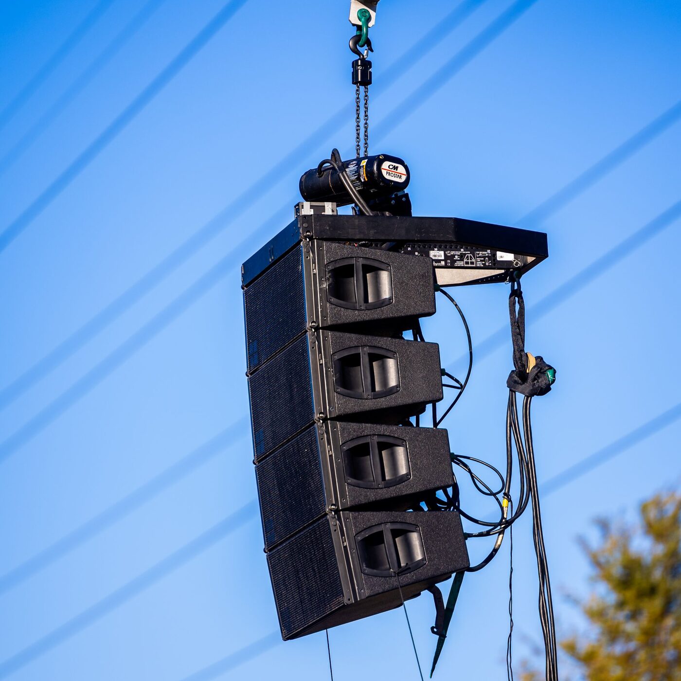 Line-array speaker cabinets flown on a hang above an open ground
