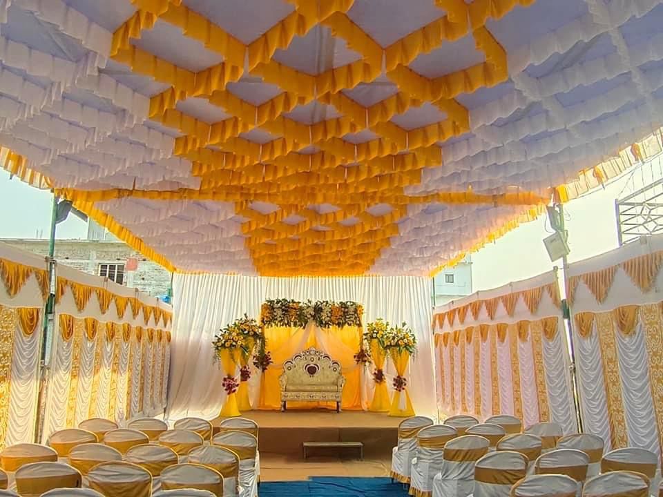Wedding mandap under a yellow and white shamiyana canopy with draped seating